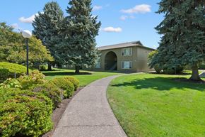Eugene apartment for rent - A pathway leads to a building with a green lawn on either side.