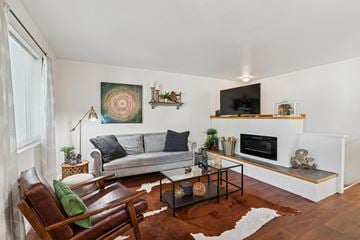 Springfield apartment for rent - A living room with a grey couch, a brown leather chair, a glass coffee table, and a painting on the wall.