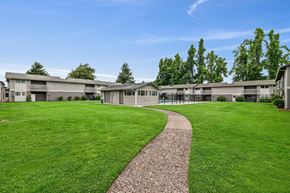Springfield apartment for rent - A grassy area with a concrete walkway leading to a building.