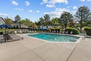 Salt Lake City apartment for rent - A large outdoor swimming pool surrounded by trees and lounge chairs.