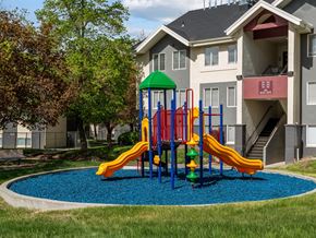 Salt Lake City apartment for rent - A playground with a green roof and a blue base is in front of a grey apartment building.