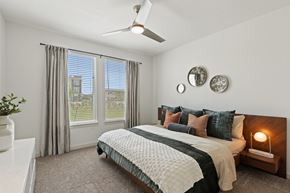 Pflugerville apartment for rent - A bedroom with a large bed and a ceiling fan.
