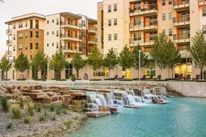 Lewisville apartment for rent - a city with a waterfall in front of some buildings at Discovery at The Realm, Lewisville
