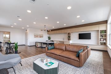 Fishers apartment for rent - A living room with a brown leather couch and a grey armchair.