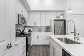 Bluffdale apartment for rent - A modern kitchen with white cabinets and stainless steel appliances.