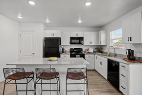 Santa Clara apartment for rent - a kitchen with white cabinets and a counter top with three stools