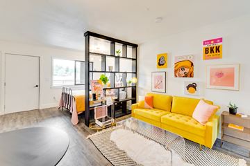 Moscow apartment for rent - a living room with a yellow couch and a desk and a window
