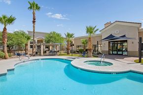 Tucson apartment for rent - A swimming pool surrounded by palm trees and a building in the background.