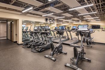 Split-level gym with adjacent shower rooms, bottle-filling station, lockers, and storage rooms