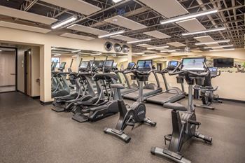 Split-level gym with adjacent shower rooms, bottle-filling station, lockers, and storage rooms