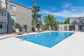 Tucson apartment for rent - A swimming pool with lounge chairs and a building in the background.