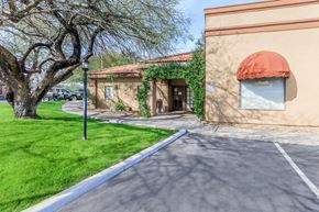 Tucson apartment for rent - A building with a red awning is situated on a street with a tree in front of it.