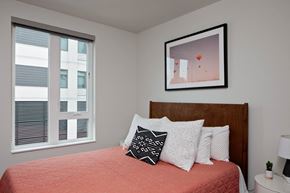 Portland apartment for rent - A bedroom with a red bedspread and a framed picture on the wall.