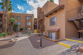 Tucson apartment for rent - A courtyard with a building in the background and a palm tree to the left.
