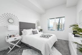 Bluffdale apartment for rent - A white bedroom with a large bed and a sunflower mirror.