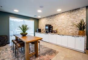 Henderson apartment for rent - A kitchen with a wooden table and chairs in front of a stone wall.