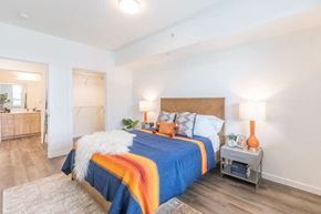 Portland apartment for rent - A bedroom with a bed covered in a blue and orange comforter.
