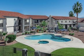 Tucson apartment for rent - A swimming pool in front of a building with a black fence around it.