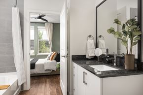 Denver apartment for rent - A bathroom with a large mirror and a bedroom with a window.