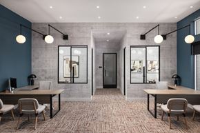 Denver apartment for rent - A modern office space with a carpeted floor, two desks with chairs, and a glass partition wall.