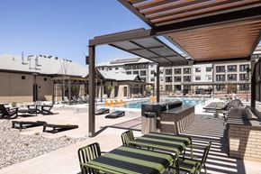 Denver apartment for rent - A pool area with sun loungers and a building in the background.