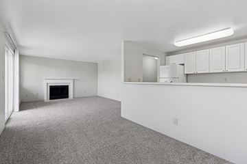 Everett apartment for rent - A sparsely furnished living room with a fireplace and a kitchen area in the background.