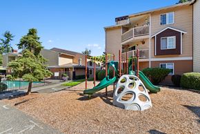 Everett apartment for rent - A playground with a slide and a climbing frame in front of a building.