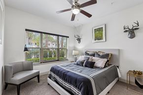 Celebration apartment for rent - A bedroom with a bed, a chair, and a ceiling fan.