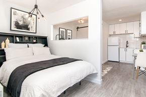 Spokane apartment for rent - a bedroom with a bed and a kitchen in the background