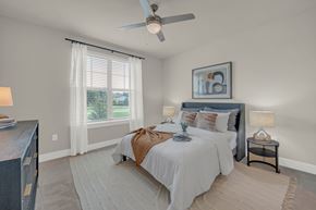 Pflugerville apartment for rent - A bedroom with a large bed and a ceiling fan.