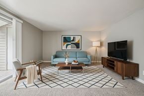 Gresham apartment for rent - A living room with a blue couch, a coffee table, a chair, a painting, a lamp, and a television.