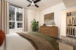 Seattle apartment for rent - A bedroom with a bed, a ceiling fan, and a window with curtains.