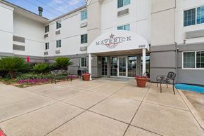 Houston apartment for rent - The entrance to the Maverick apartment complex is shown with a red flower in a pot.