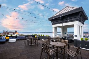 Tacoma apartment for rent - a rooftop patio with tables and chairs and a view of the water