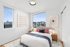 Portland apartment for rent - A bedroom with a large bed and a view of the city.