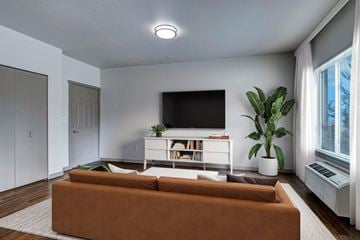 Bend apartment for rent - A living room with a brown couch and a flat screen TV mounted on the wall.