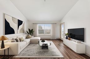 Eugene apartment for rent - A modern living room with a white sofa, a coffee table, a large painting, a flat screen TV, and a window with curtains.