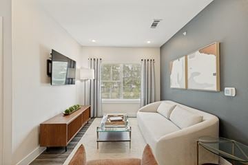 Spring apartment for rent - A modern living room with a white sofa and a wooden bench.