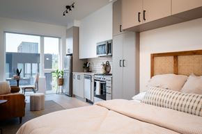 Portland apartment for rent - A modern bedroom with a large bed and a kitchen area in the background.