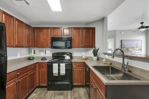 Tucson apartment for rent - A kitchen with wooden cabinets and black appliances.
