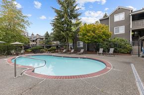 Lynnwood apartment for rent - a swimming pool with chairs and a building in the background