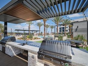 Chula Vista apartment for rent - A modern outdoor dining area with a long table and chairs under a pergola.