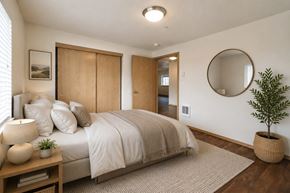 Washougal apartment for rent - A bedroom with a bed, a plant, and a round mirror on the wall.