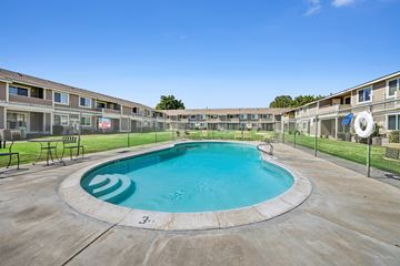 Kennewick apartment for rent - A round swimming pool in the middle of a concrete area with buildings in the background.