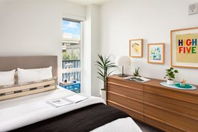 Seattle apartment for rent - A bedroom with a bed, nightstand, and a window overlooking a cityscape.