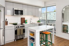 Seattle apartment for rent - A modern kitchen with white appliances and green stools.