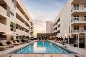 Phoenix apartment for rent - A large swimming pool in the middle of a courtyard surrounded by lounge chairs and umbrellas.