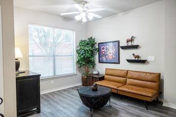 San Antonio apartment for rent - A living room with a brown couch, a black coffee table, and a framed picture on the wall.