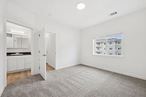 Gillette apartment for rent - A spacious room with a grey carpet and a window showing a building outside.