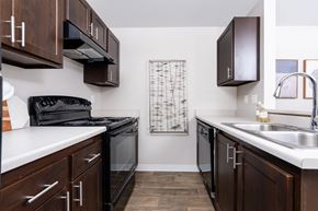 Silverdale apartment for rent - a kitchen with dark wood cabinets and white counter tops and a black stove and sink